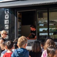 Backs of student heads as they gather in front of a food truck who is taking orders.